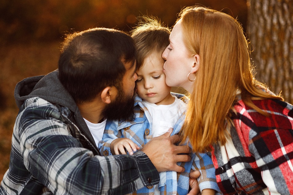 Parents kissing their son during an autumn family session at Minnewasta