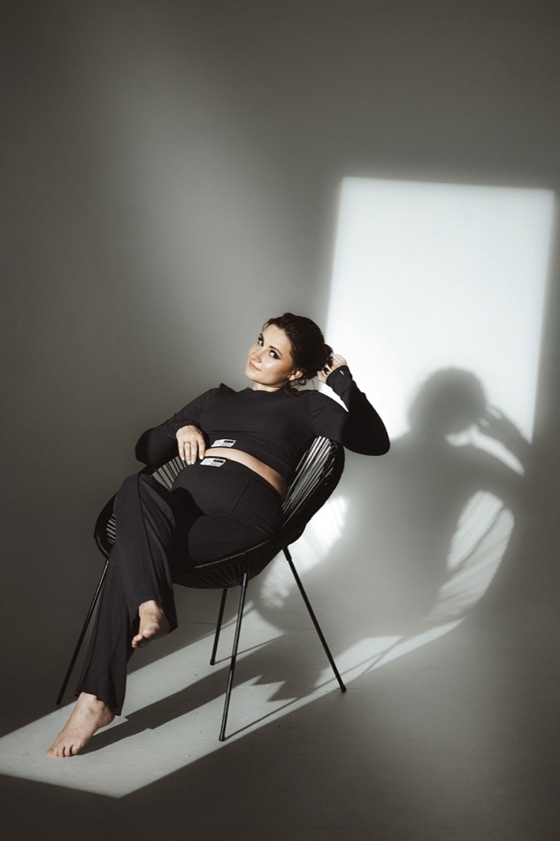 Seated maternity portrait with sculptural window light and shadows