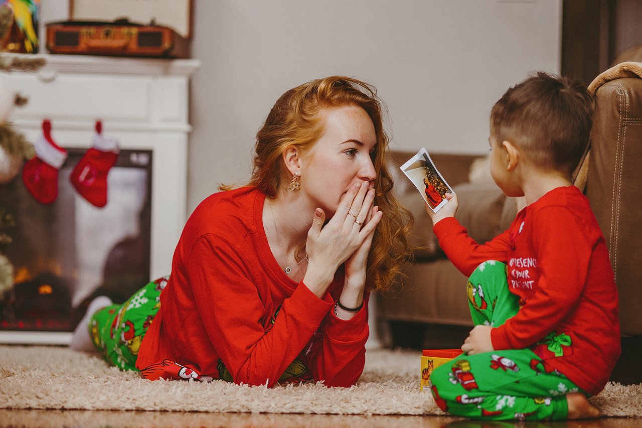 Alina and her son David playing together on the floor beside the Christmas tree.