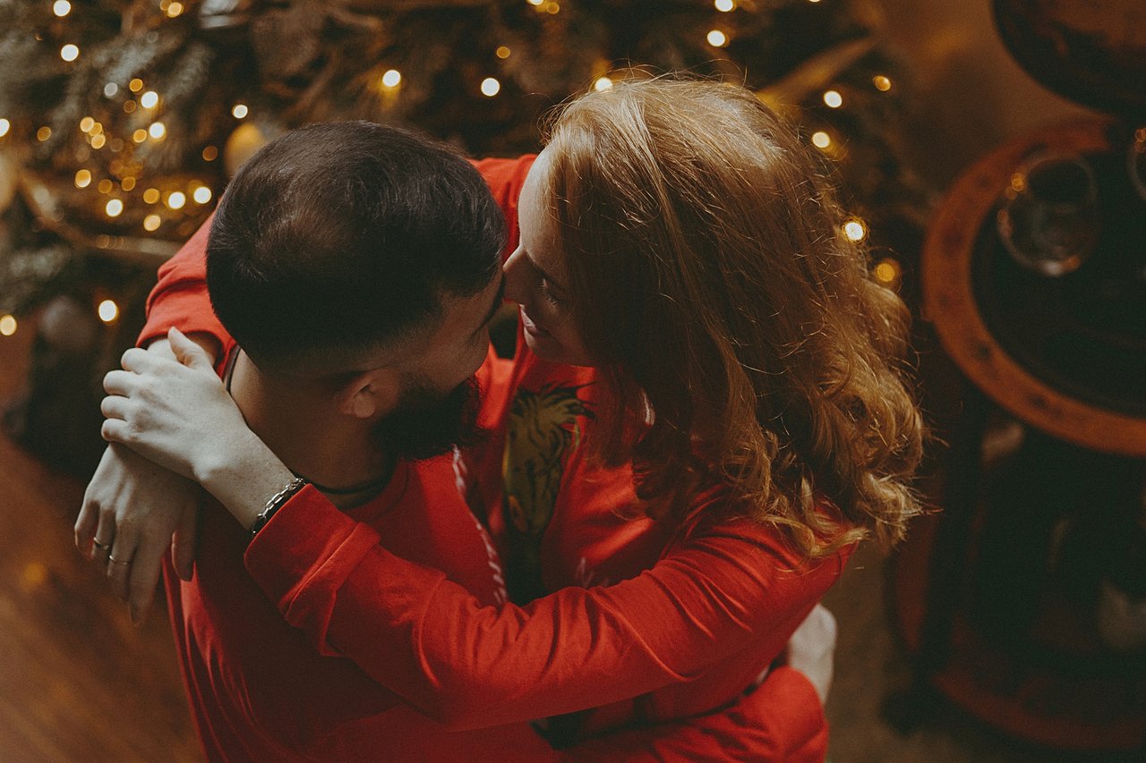 Alina and Nurali embracing beside the Christmas tree during their home session.