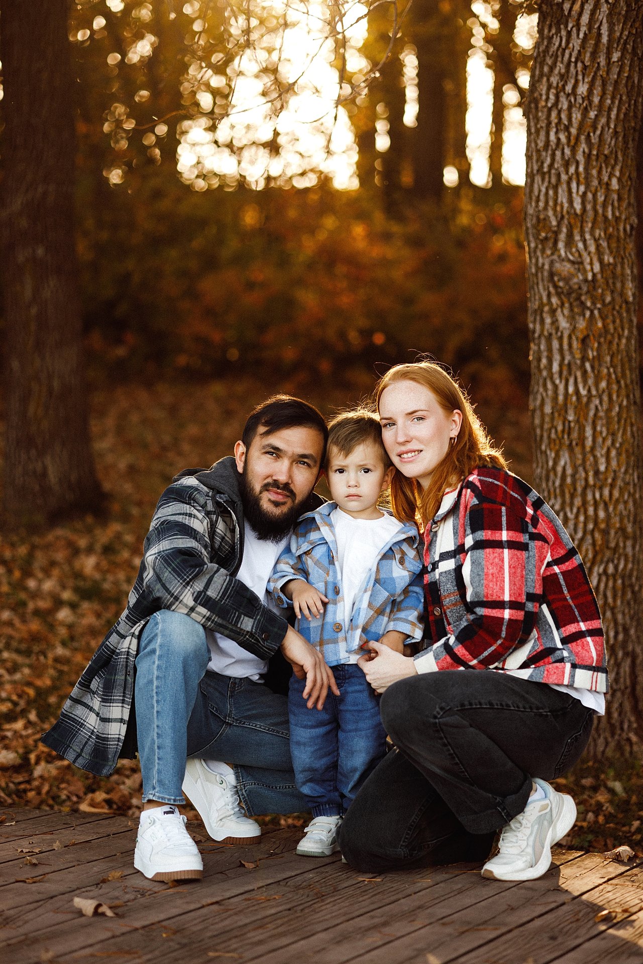Alina and Nurali crouching beside their son David during an autumn family session at Minnewasta.