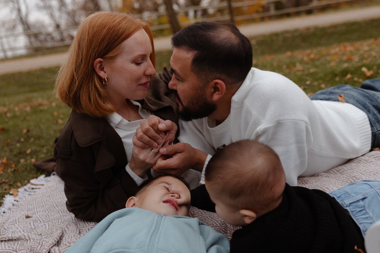 Alina and Nurali sharing a kiss while sitting close to their children.