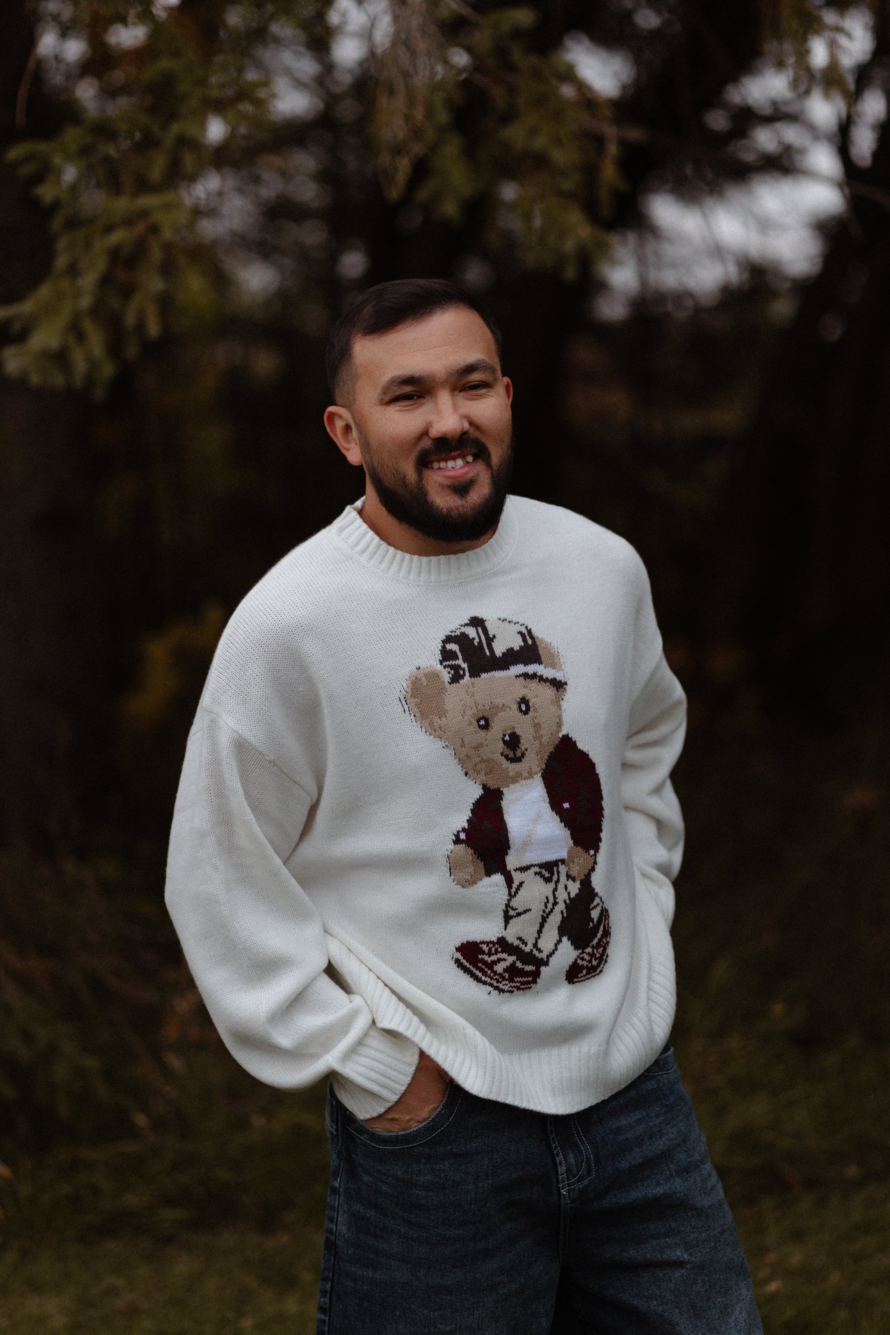 Portrait of Nurali seated outdoors in his white sweater.