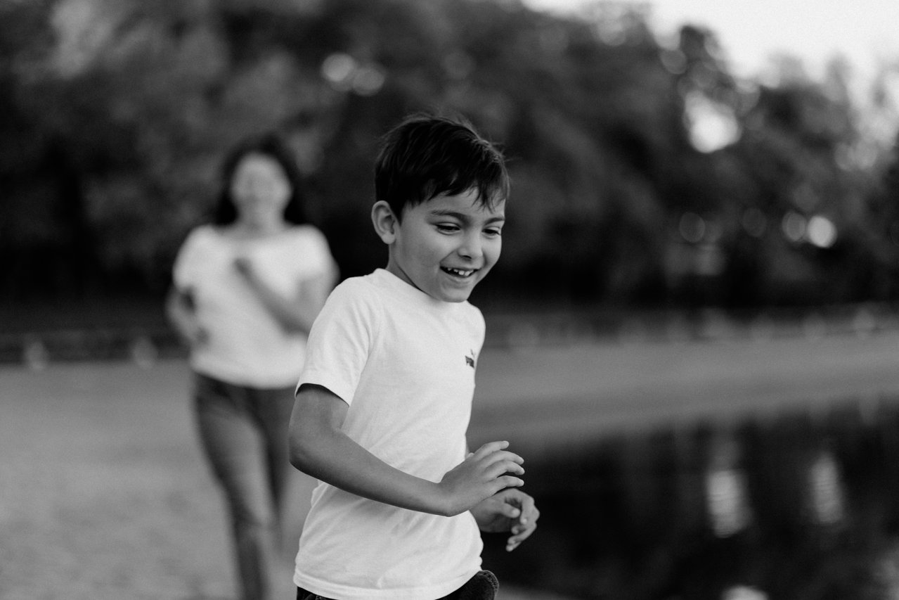 Black and white photograph of a child moving through the foreground with his mother behind him at Minnewasta.