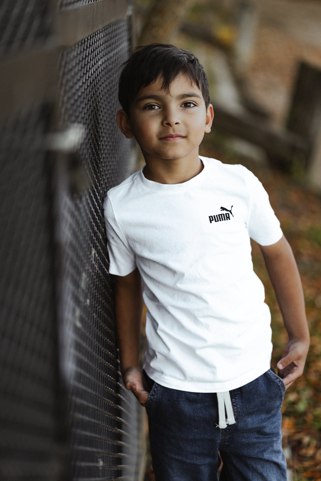 Child looking towards the camera beside a wooden railing during an outdoor family session.