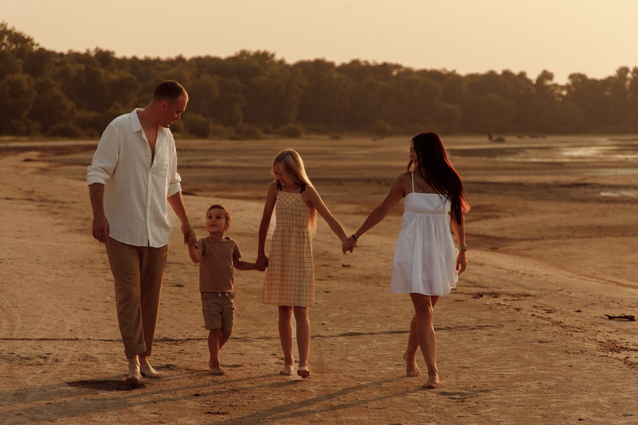 Family walking together along the shoreline in warm evening light