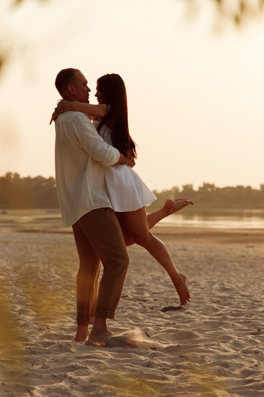 Couple holding each other close beside the water