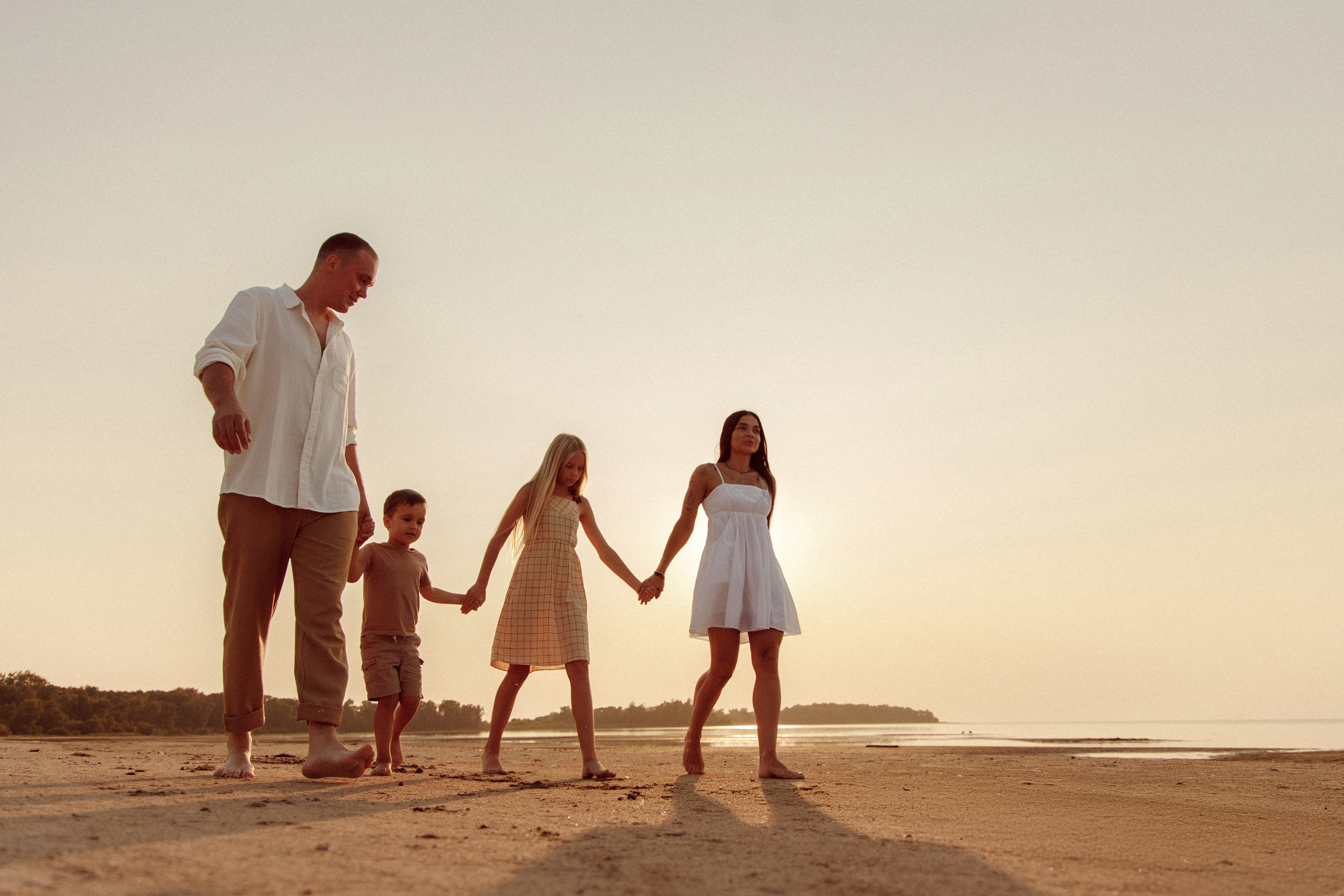 Family walking together beside the water in warm evening light